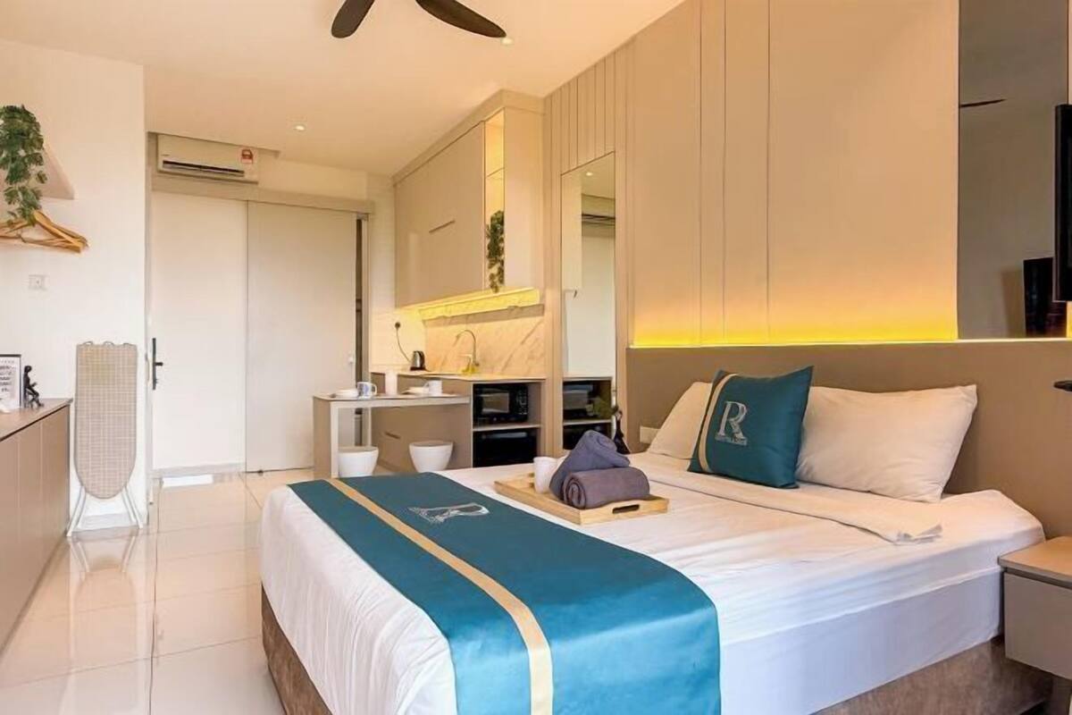 Una camera d'albergo con un letto, un comodino e una scrivania con una sedia.