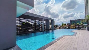 A swimming pool with a modern architectural design, surrounded by a wooden deck and a clear sky.