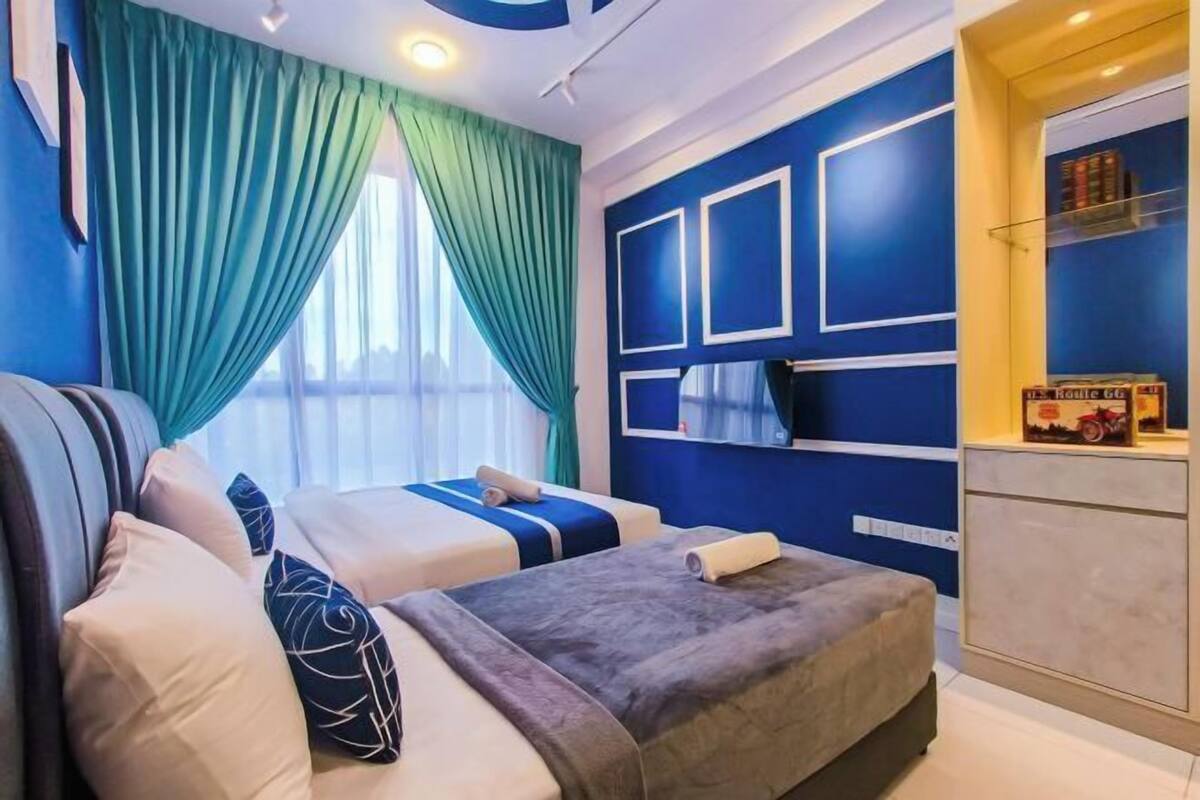 Camera d'albergo con due letti, un divano, una scrivania e una finestra con tende.