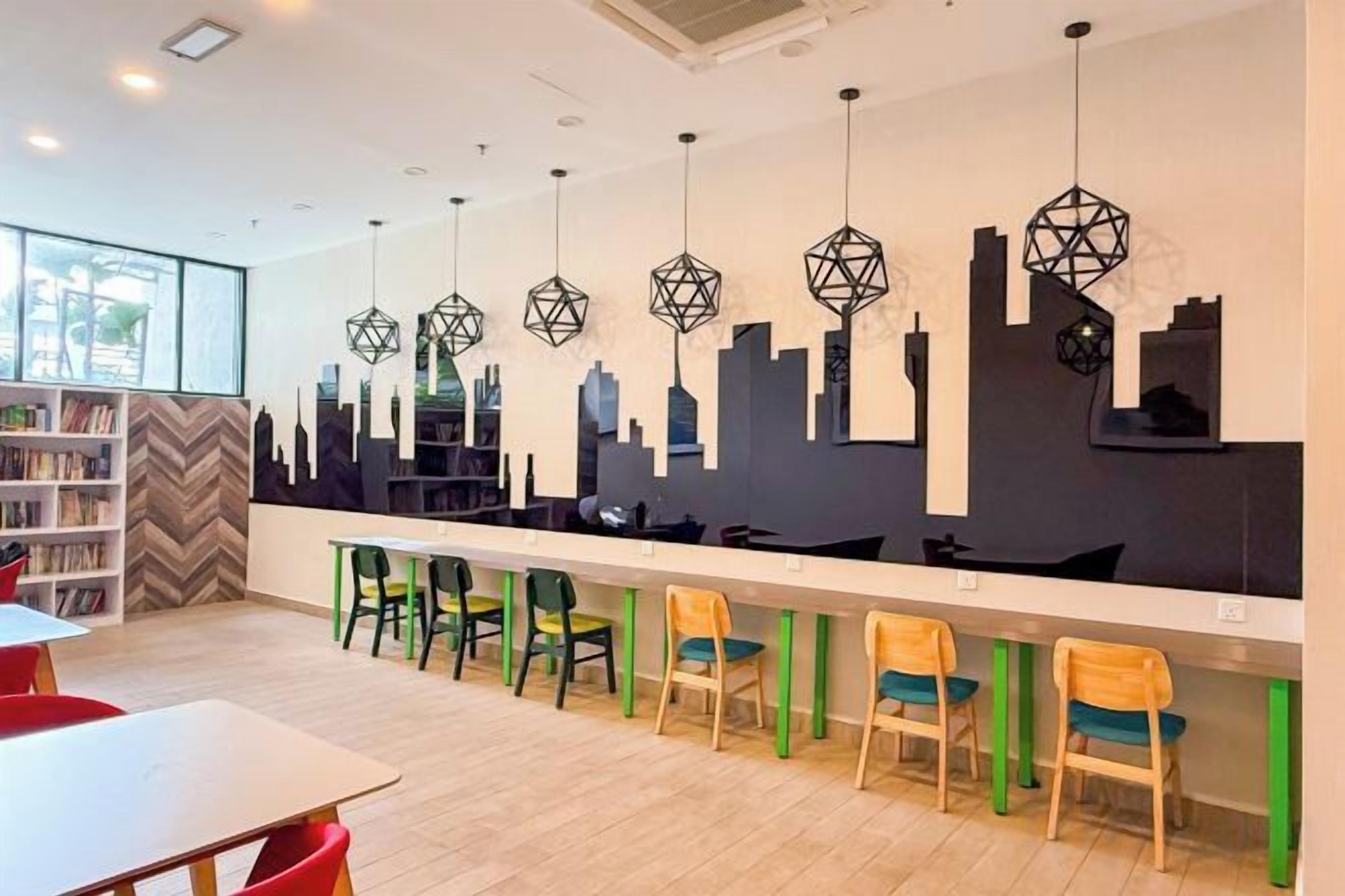 Un área de bar moderna con un mural de la ciudad, distintas opciones de asientos y una barra larga.