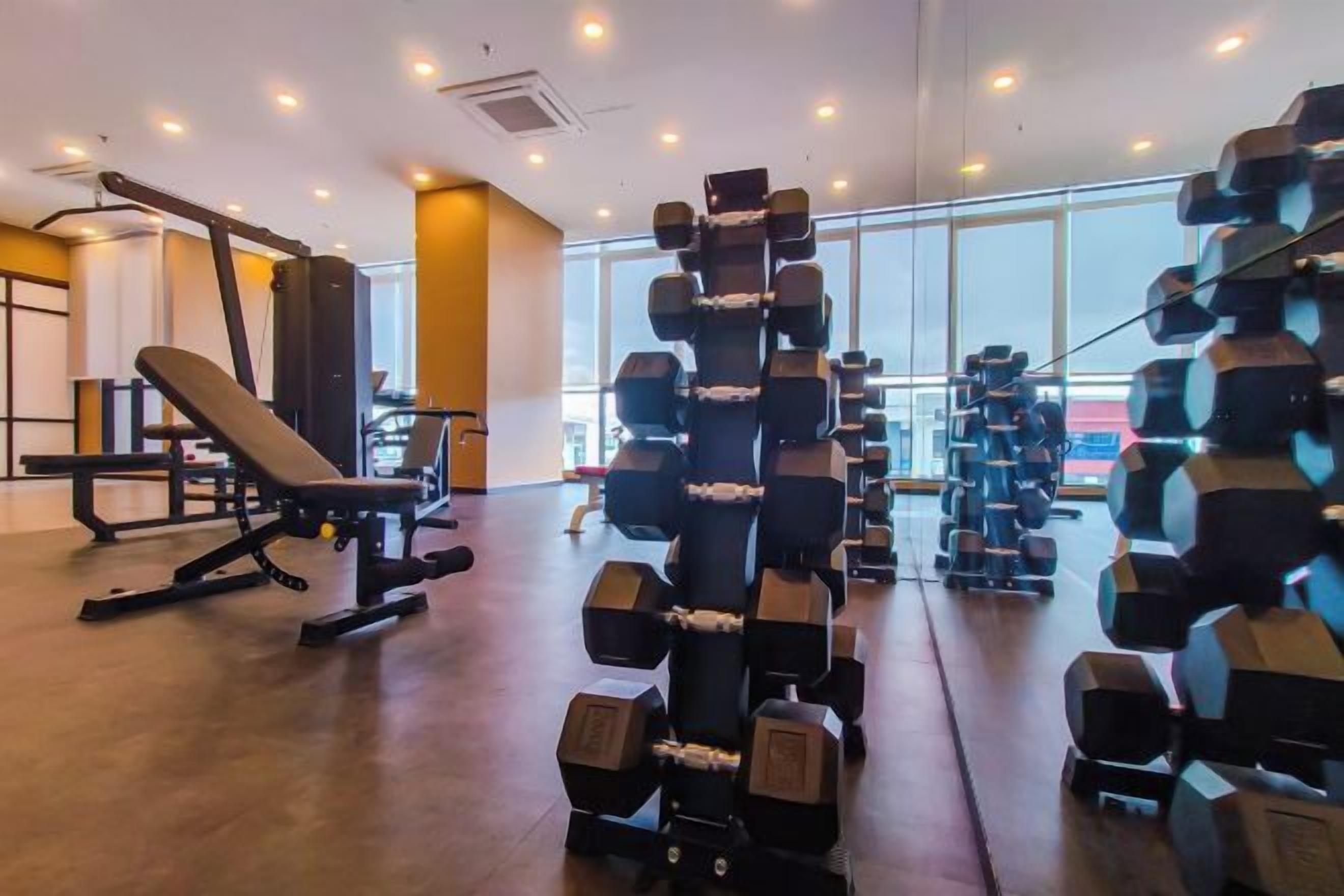 A gym with weightlifting equipment, benches, and a large window.