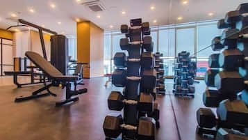 A gym with weightlifting equipment, benches, and a large window.