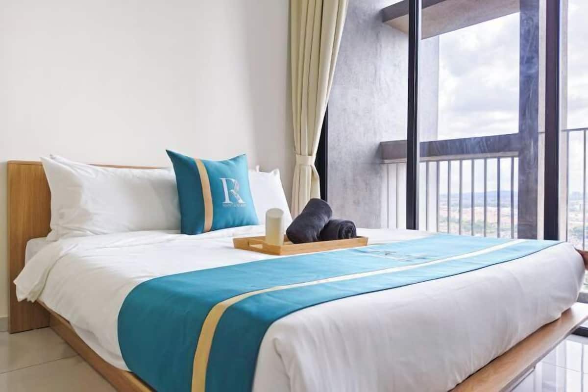 Camera d'albergo con un letto grande, vista all'esterno, una testiera in legno e una finestra con tende.