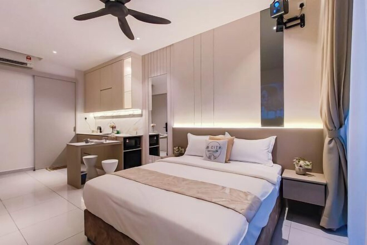 A modern hotel room with a large bed, a desk, a vanity, and a ceiling fan.