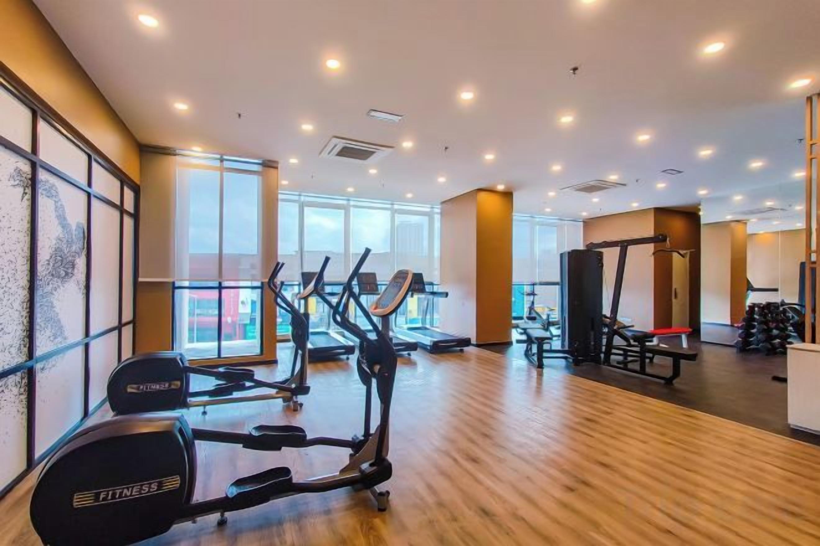 A gym with cardio machines, weightlifting equipment, and large windows.