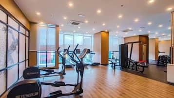 A gym with cardio machines, weightlifting equipment, and large windows.