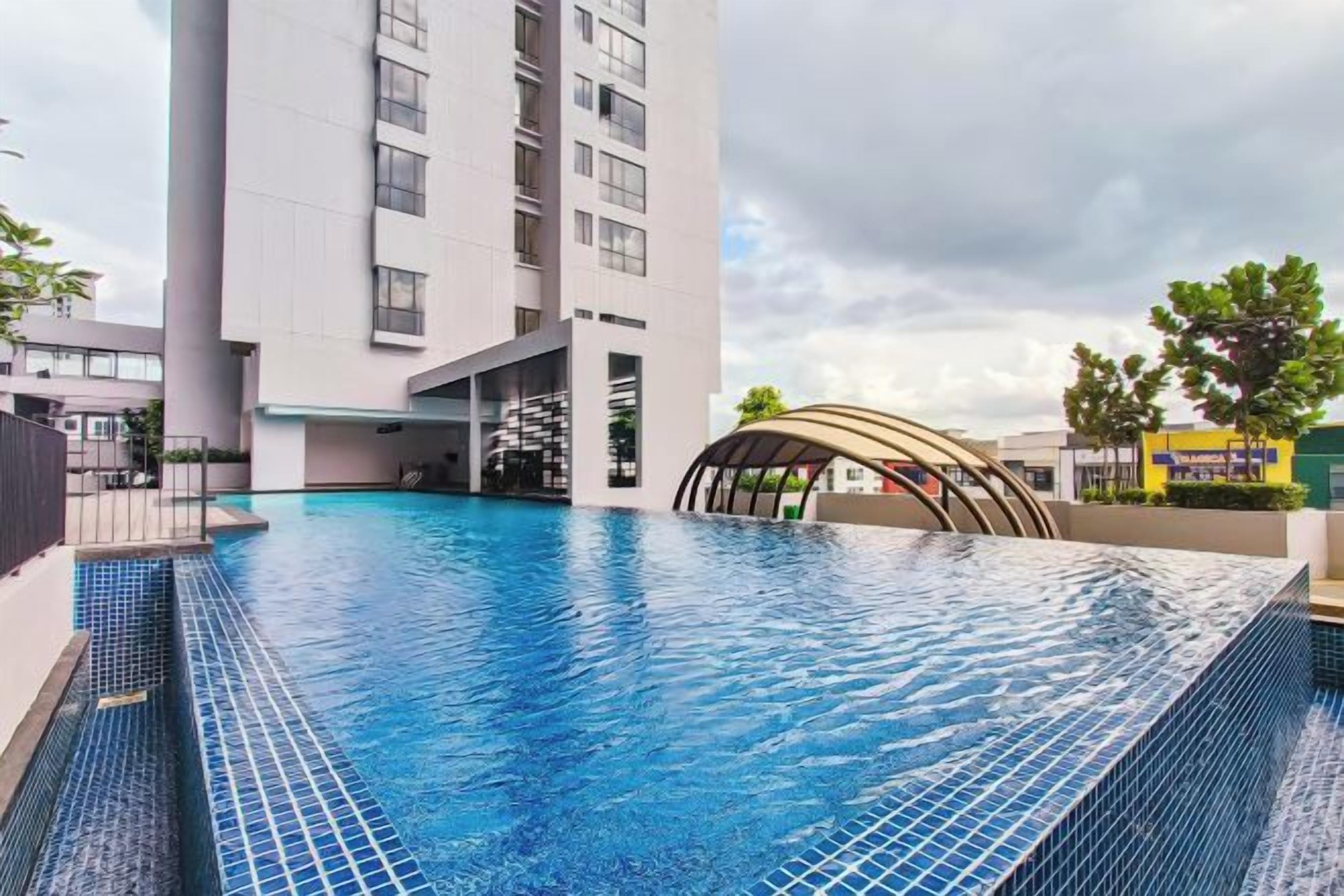 Une piscine située à côté d’un bâtiment moderne doté d’une toiture aux lignes courbes.