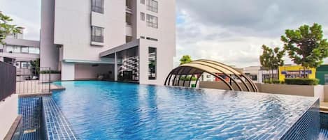 Une piscine située à côté d’un bâtiment moderne doté d’une toiture aux lignes courbes.