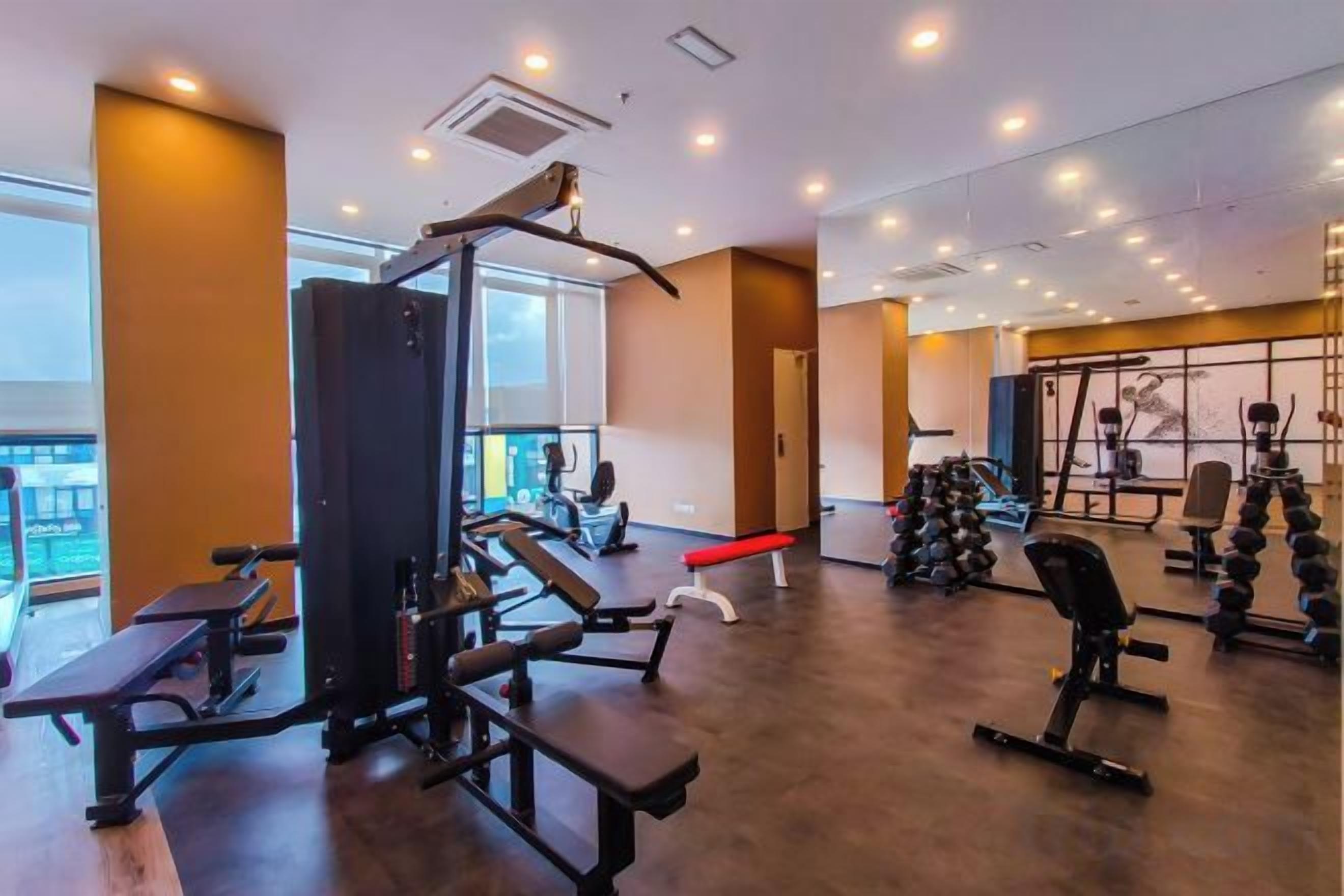 A gym with various exercise equipment, including a squat rack, benches, and dumbbells.