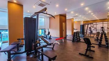 A gym with various exercise equipment, including a squat rack, benches, and dumbbells.