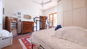 Een slaapkamer met een bed, een dressoir, een kledingkast en een plafondventilator.