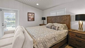 Ein Schlafzimmer mit einem großen Bett, einem Holzkopfteil, einem Nachttisch mit Lampe und einem Fenster mit Jalousien.