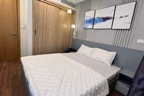 A bedroom with a bed, bedside tables, a wardrobe, and wall-mounted artwork. - FLC Quy Nhon Beachfront Condotel (Quy Nhon)