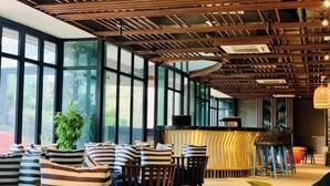 A modern interior with a bar area, large windows, and striped cushions on chairs.