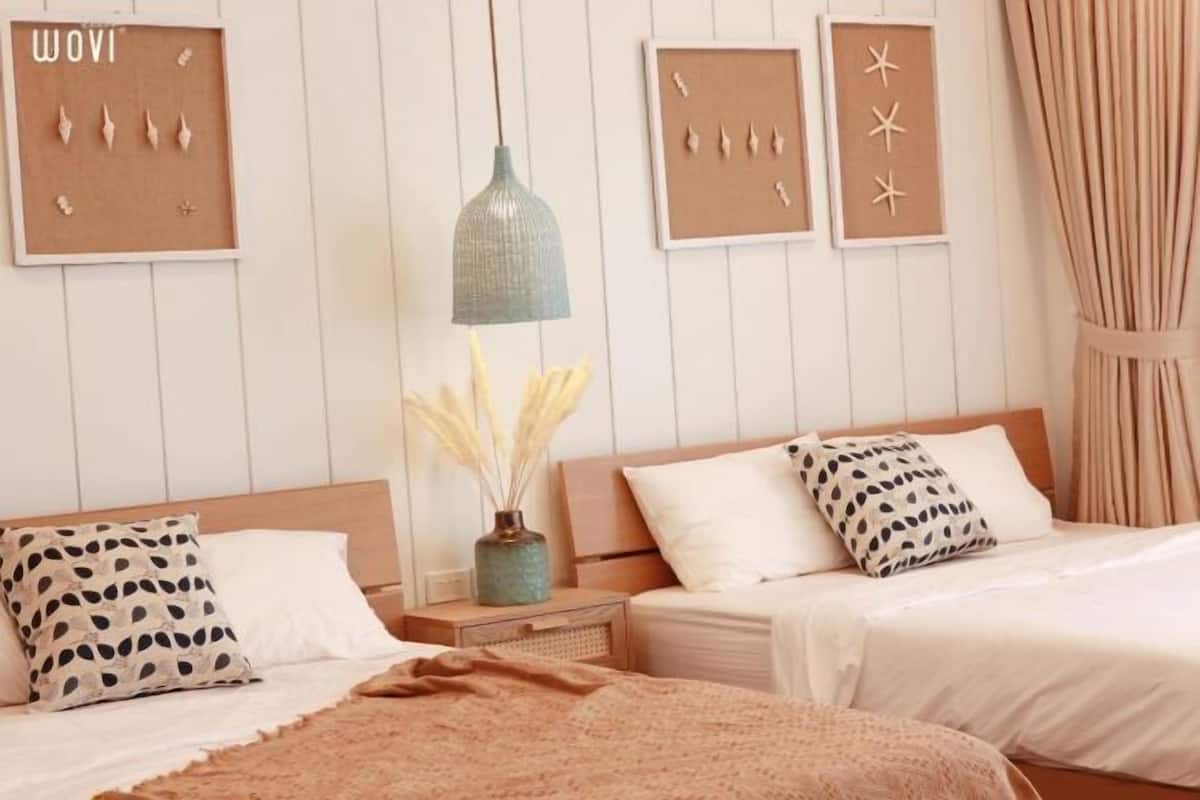 A bedroom with two beds, a nightstand, a lamp, and wall art.