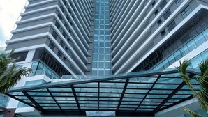 A high-rise building with a modern architectural design, featuring a central glass facade and a symmetrical structure.