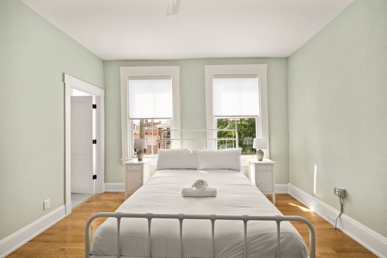 A bedroom with a bed, two bedside tables, a window, and a door.