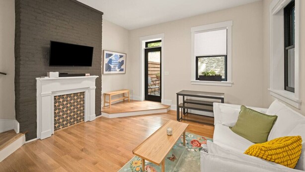 A living room with a fireplace, a television, a dining area, and a window with a view. - Hidden Gem 2BD w/ Patio, Near Findlay Market, UC (Cincinnati)