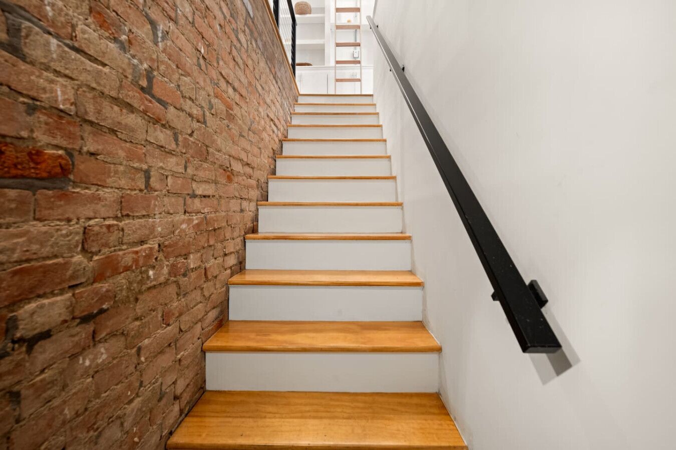 A staircase with wooden steps and a brick wall on one side.