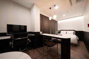 A hotel room with a bed, a desk, a chair, a TV, and a curtain.