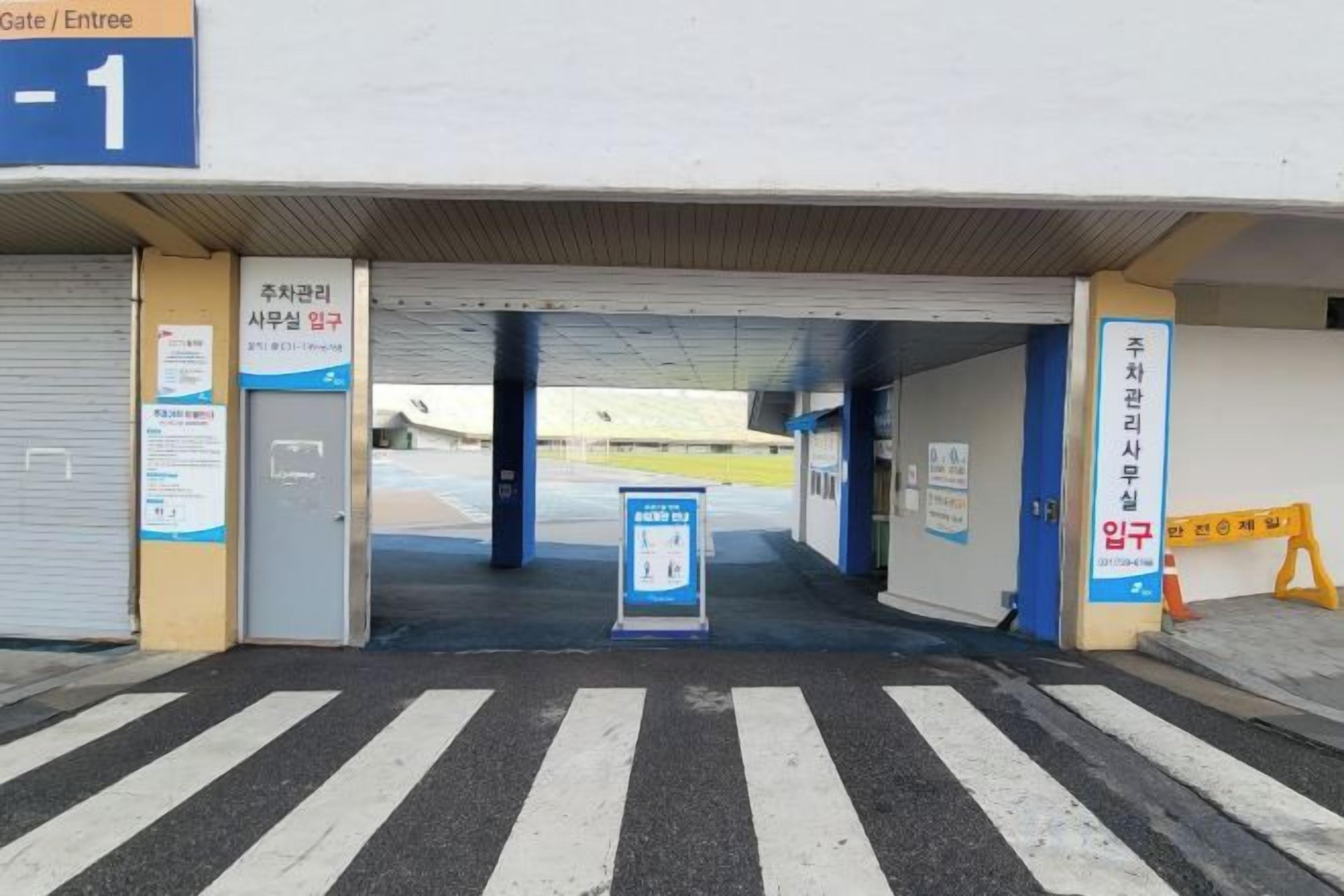 A covered entrance to a building with a blue sign indicating 'Gate / Entrée -1'.