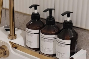 Three bottles of Moment brand shampoo, conditioner, and body gel on a bathroom counter. - Hotel Label Seongnam (Seongnam)
