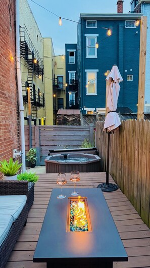 A patio with a fire feature, outdoor seating, and a hot tub.