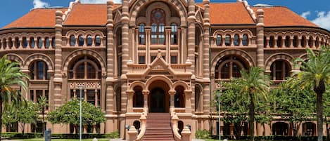 A large, historic building with a symmetrical facade, arched windows, and a central entrance with steps.