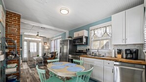 A kitchen with white cabinets, a stainless steel refrigerator, and a wooden countertop. - Sunny Craftsman Cottage Close To Seawall & Strand (Galveston)