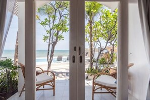 A view through a glass door to a beachside area with wicker chairs and potted plants. - Baan Kangmung HuaHin Resort (Hua Hin)