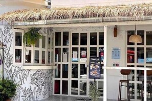 A restaurant with a thatched roof, large windows, and a mural of a tiger. - Baan Kangmung HuaHin Resort (Hua Hin)