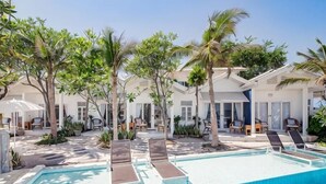 A pool area with lounge chairs, palm trees, and a clear blue sky. - Baan Kangmung HuaHin Resort (Hua Hin)