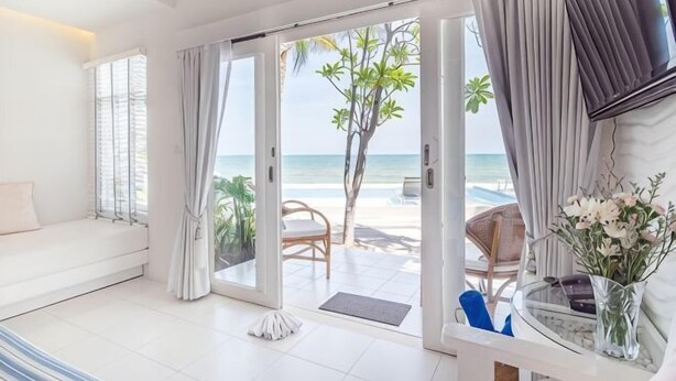 A room with a sofa, a chair, a desk, a TV, and a view of the beach. - Baan Kangmung HuaHin Resort (Hua Hin)