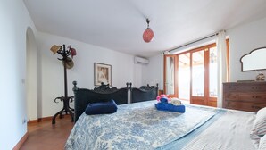 Un dormitorio con cama, cómoda, perchero y ventana con cortinas.