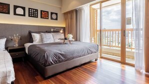 A bedroom with a large bed, a nightstand, a dresser, and a balcony with a view.