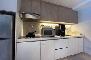 Eine moderne Küche mit weißen Schränken, einem Edelstahlkühlschrank, einer Mikrowelle und einer Kaffeemaschine.