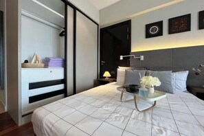 Ein modernes Schlafzimmer mit Bett, Nachttisch, Lampe und einem Kunstwerk an der Wand.