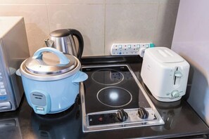 Eine Küche mit einem blauen Slow-Cooker, einem Wasserkocher, einem Toaster und einem Herd.
