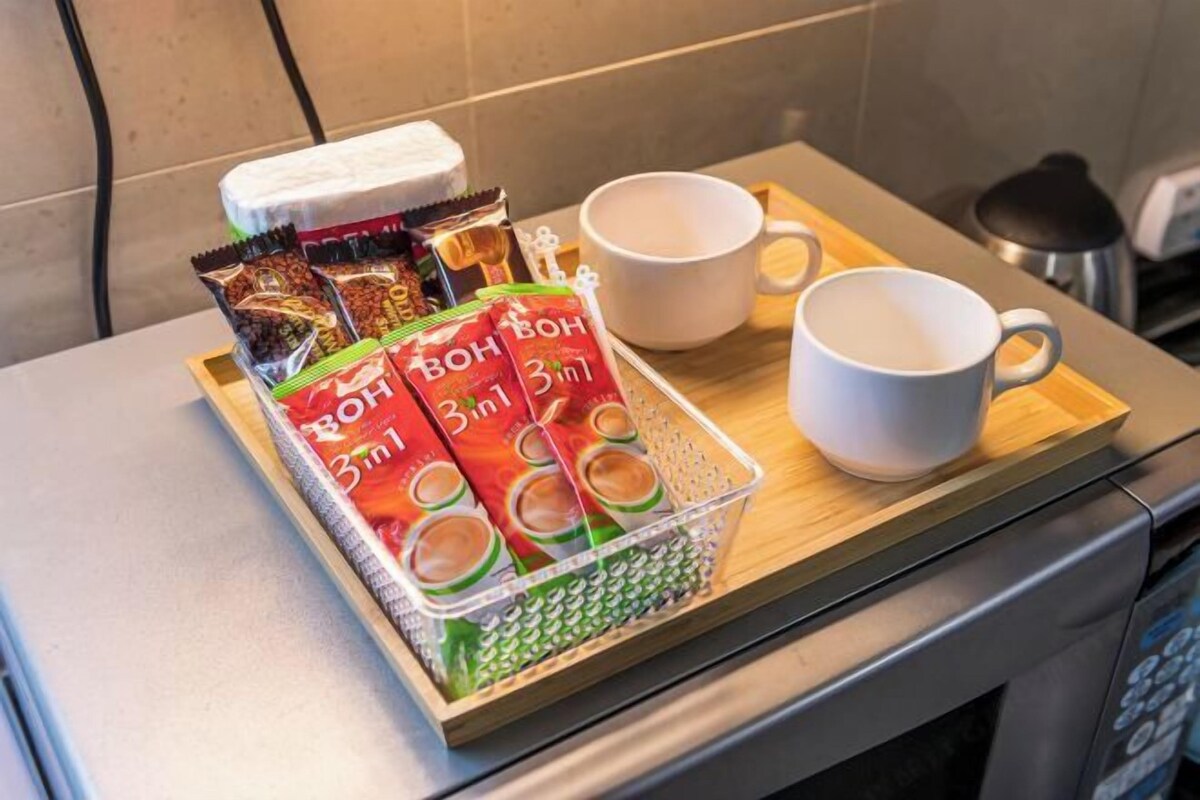 Eine Schale mit verpackten Snacks und zwei weißen Tassen auf einem Holztablett.