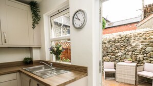 Una cocina con pared de piedra y un reloj.