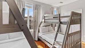 Una habitación con literas, una ventana con cortinas y una puerta.