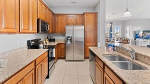 Una cocina moderna con armarios de madera, electrodomésticos de acero inoxidable, encimeras de granito y un lavabo doble.