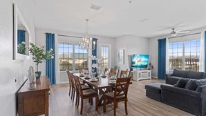 Un salón espacioso con comedor, un sofá gris y un televisor.