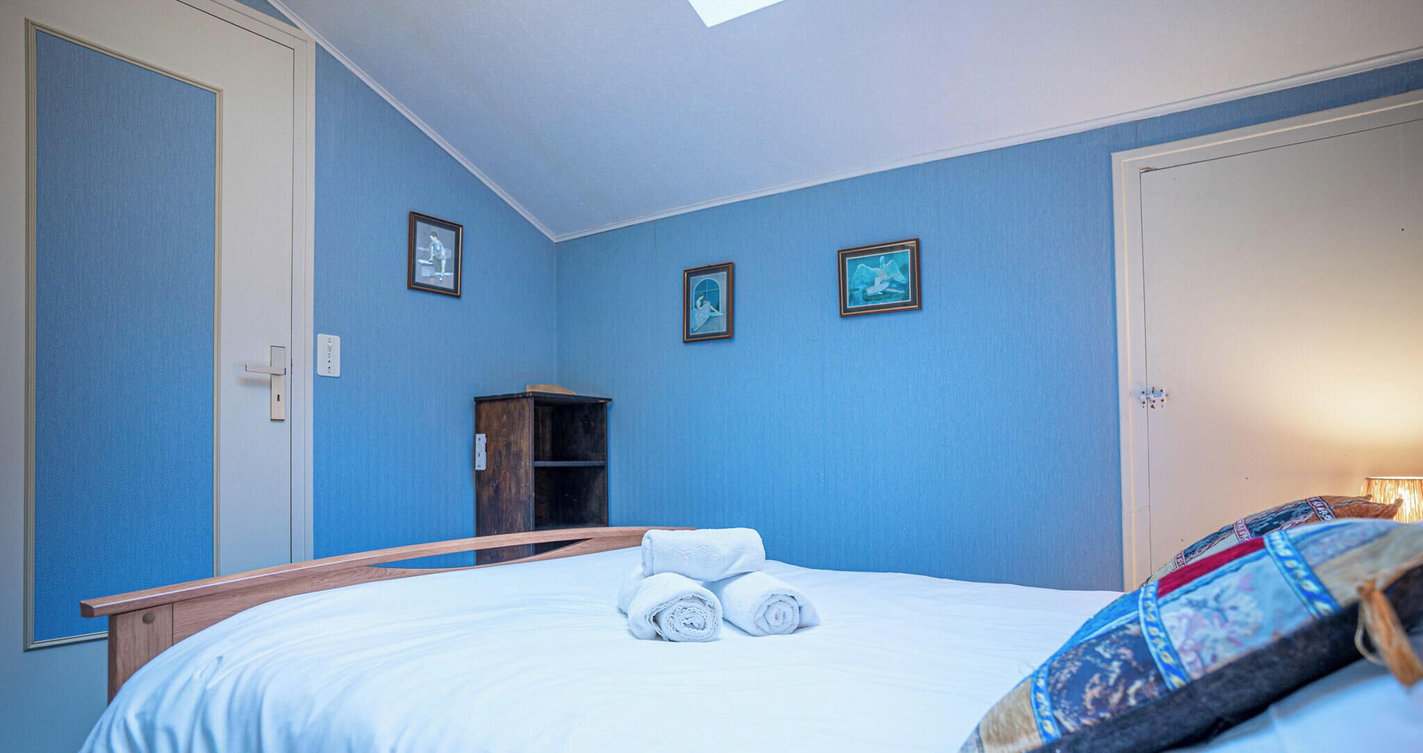 Ein Schlafzimmer mit einem Bett, einem Holz-Kopfteil, einem Kleiderschrank und einem Oberlicht.