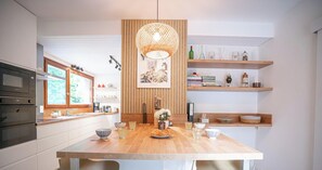 Une cuisine moderne avec des plans de travail en bois, un îlot central et des étagères intégrées.