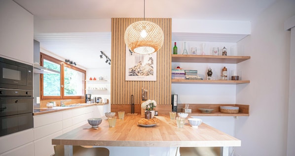 Una cocina moderna con una isla de madera, electrodomésticos integrados y una lámpara colgante.