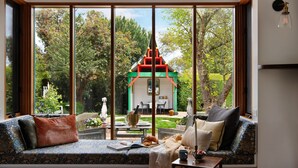 Ein gemütlicher Sitzbereich mit Blick auf einen kleinen Garten und ein Gebäude mit rotem Dach.