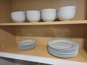 Ein Küchenregal mit weißen Schüsseln und Tellern.