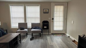 Uma sala de estar com sofá, duas poltronas, uma mesa de centro e lareira.