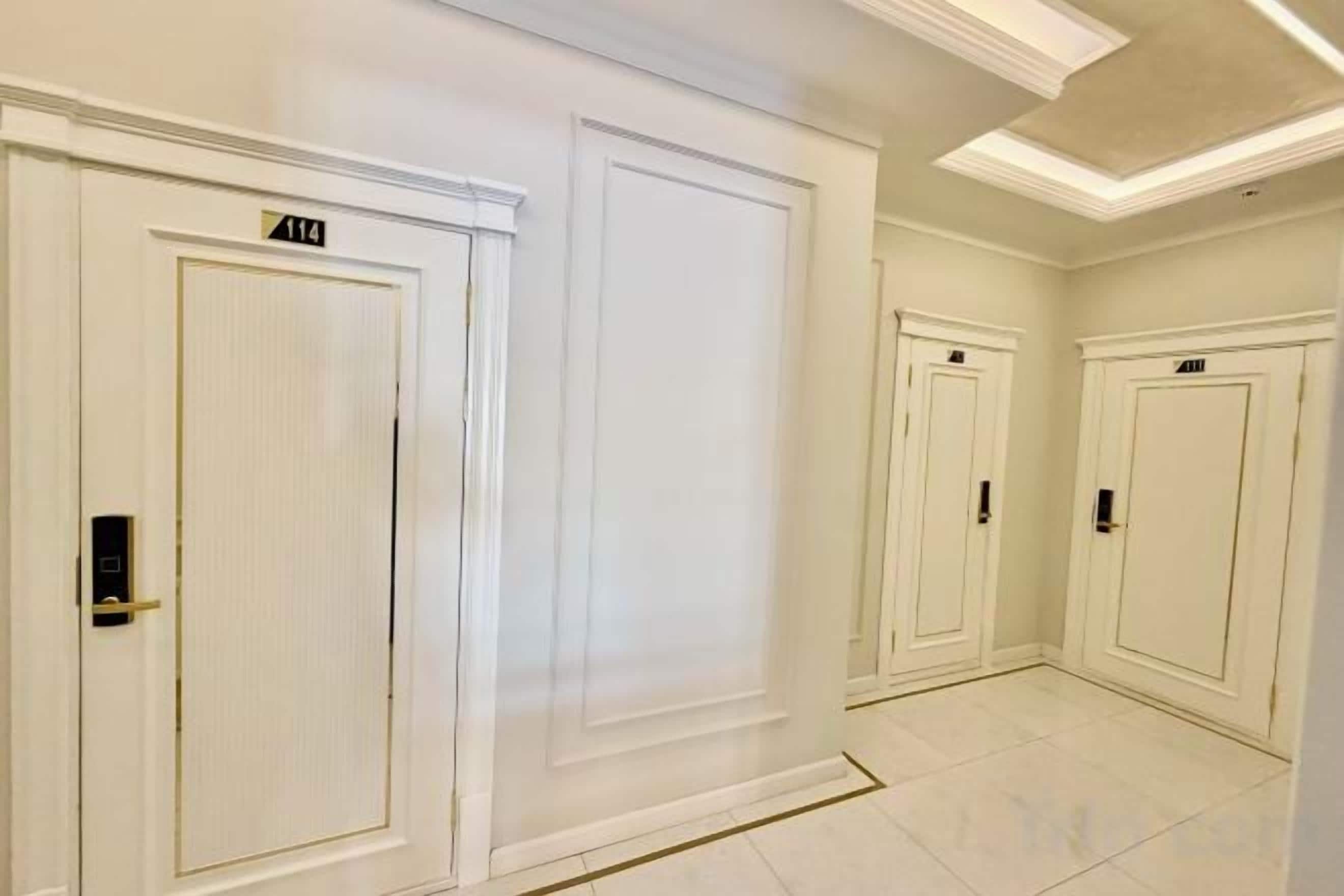 A hallway with white doors, each marked with a number.